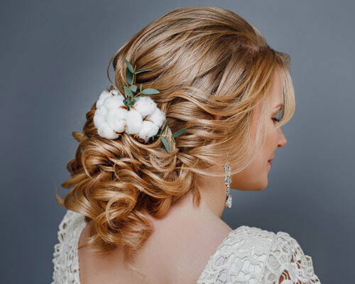 Eine junge Frau im Brautkleid, hübsch geschminkt mit wunderschöner Hochzeitsfrisur und passendem Schmuck.